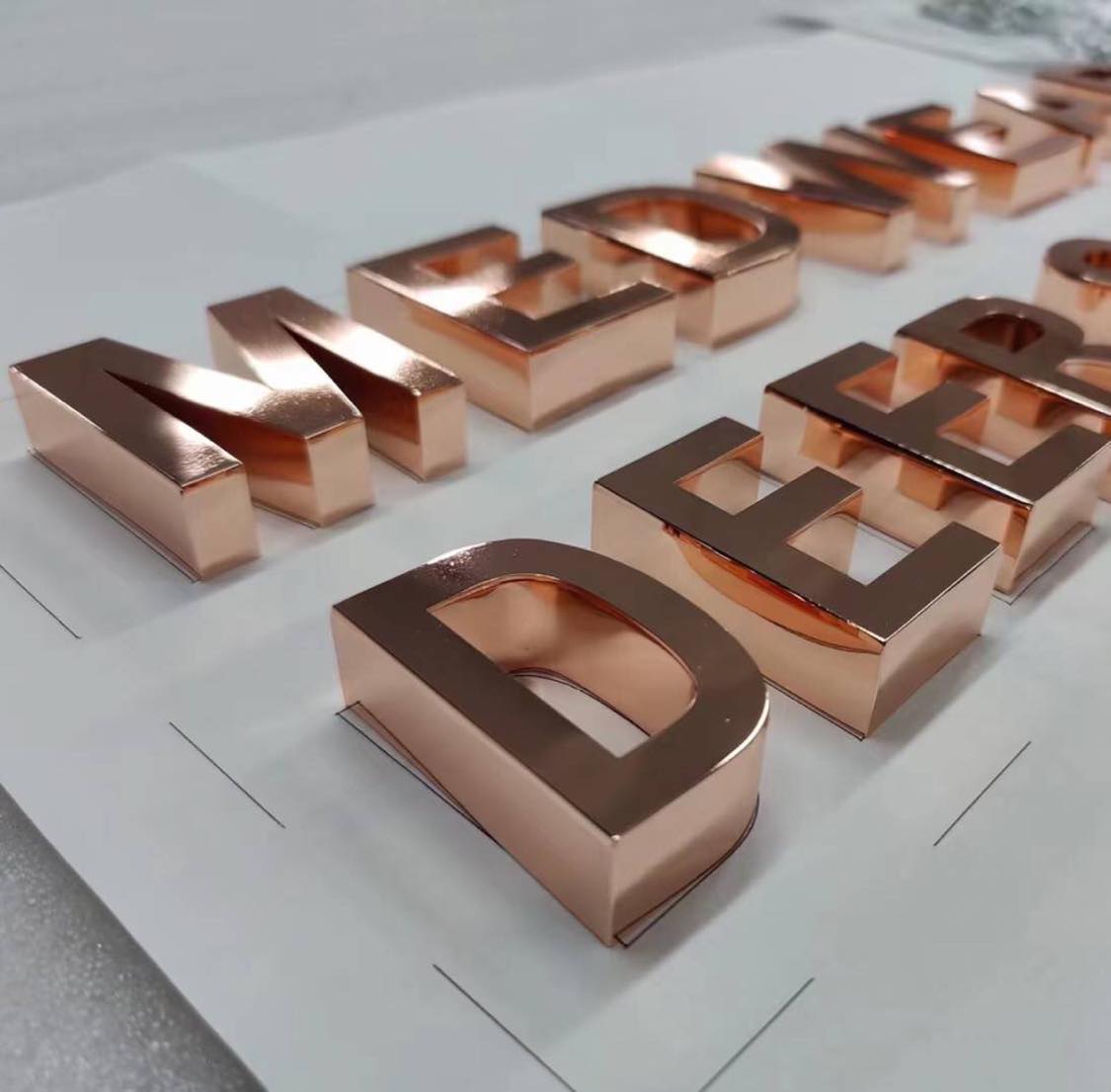 close up of rose gold mirrored effect metallic finish letters on a table spread out
